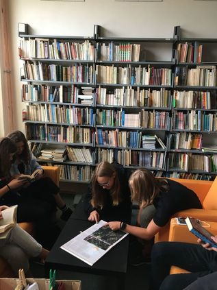 ilustrační foto - žáci sedí u stolu v knihovně a společně pracují s četbou